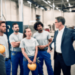 A facility manager giving presentation to group of industrial workers in a factory